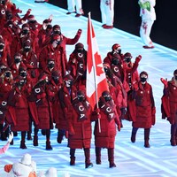 Une dizaine d'athlètes habillés de gros manteaux d'hiver, de foulard et de tuques qui marchent ensemble. 