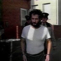 Allan Legere menotté et amené par deux policiers à son procès.