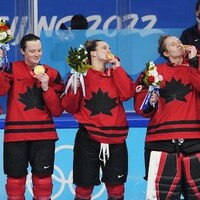 Des joueuses d'Équipe Canada embrassent la médaille d'or qu'elles portent à leur cou.