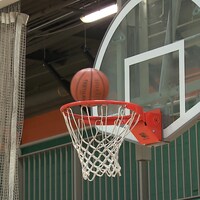 Un ballon en suspension au-dessus de l'anneau d'un panier de basketball. 