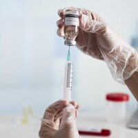 Une seringue et un vaccin se font manipuler en laboratoire.