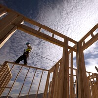 Un travailleur debout sur la structure d'une maison en construction