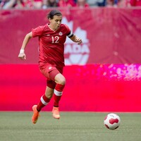 Une joueuse en rouge court avec le ballon.