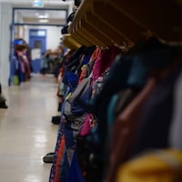 Corridor de l'école primaire où des manteaux sont accrochés aux crochets des casiers d'élèves.