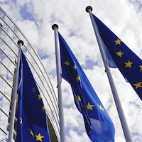 Trois drapeaux de l'Union européenne devant le parlement européen.
