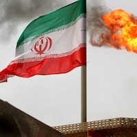 Le drapeau iranien vole au vent, alors que la torche crache du feu.