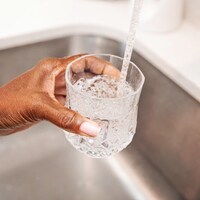 Une personne se sert un verre d'eau directement du robinet.