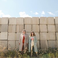 Les artistes éemi et Marie-Clo sont dehors devant un grand mur.