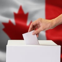 Une main dépose un bulletin de vote dans une urne.