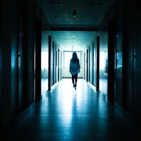 Une jeune femme marche dans un corridor sombre.