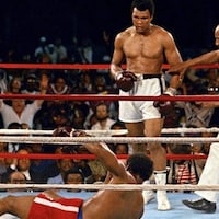Sur un ring de boxe, Muhammad Ali regarde George Foreman tomber par terre, tandis qu'un arbitre s'apprête à toucher son bras.