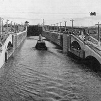 Photo en noir et blanc montrant un bateau à vapeur dans un canal étroit.