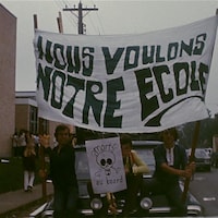 Des adolescents tiennent une grande bannière sur laquelle on peut lire : « Nous voulons notre école ».