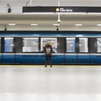 Une personne attend sur le quai de la ligne orange alors que le métro s'immobilise sur les rails.