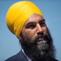 Un homme avec un turban jaune est photographié plan épaule sur fond bleu.