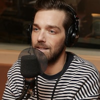 Un homme parle devant un micro dans un studio de radio.