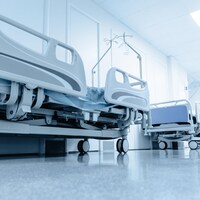 Des lits d'hôpital alignés dans un corridor.
