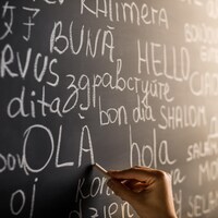 Le mot « bonjour » écrit en plusieurs langues sur un tableau d'école.