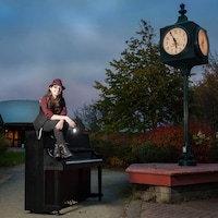 Une femme assise sur un piano, en plein air, au clair-obscur