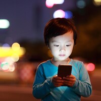 Un bambin est captivé par l'écran d'un téléphone portable.