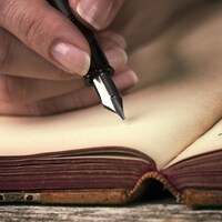 Une personne s'apprête à écrire des mots dans une nouvelle page d'un ouvrage.