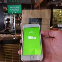 Une main tenant une téléphone cellulaire qui affiche l'application Uber Eats.