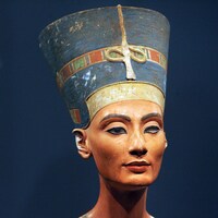 Une sculpture égyptienne représentant la tête de la reine avec un haut chapeau.