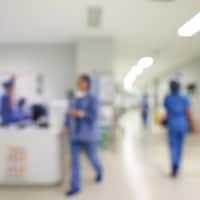Image floue de travailleurs de la santé dans un corridor d'hôpital.