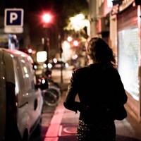Une femme marche dans la rue la nuit. 
