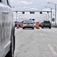 Des policiers parlent à des automobilistes sur le pont, entourés de cônes orange.