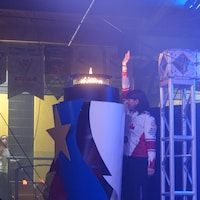 Une personne et la flamme des Jeux de l'Acadie.