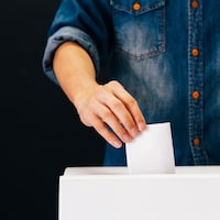 Un électeur qui tient un bulletin dans un bureau de vote.
