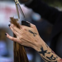 Une coiffeuse coupe les cheveux d'une femme. 