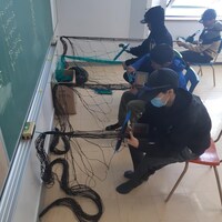 Des élèves fabriquent des filets de pêche dans une salle de classe.