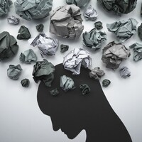 Illustration en papier d'une tête qui a des pensées troubles représentées par des boules de papier froissées.