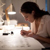 Une femme assise à une table en train de dessiner.