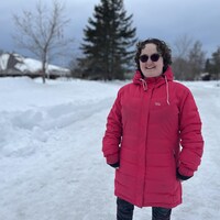 Julie Bourque en manteau d'hiver et lunette de soleil, dans un arrière-plan enneigé.
