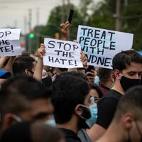 Des personnes manifestent avec des pancartes « Arrêtons la haine ».