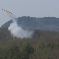 Un avion largue un produit sur la forêt pour éteindre l'incendie.