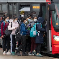 Des personnes masquées montent dans un autobus.