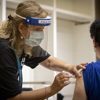 Healthcare providers with Unity Health Toronto administer the Pfizer-BioNTech COVID-19 vaccine at a one-day pop-up clinic in the Eaton Centre mall, in Toronto, on July 27, 2021.