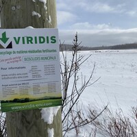 Une affiche de Viridis devant un champs. 