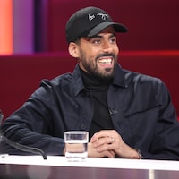 Adib Alkhalidey est à la table des invités. Il porte une casquette, une veste et un chandail noirs.
