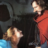 Une femme en robe d'époque (Anne Brochet), assise, lève le visage vers un homme en cape rouge et au nez proéminent (Gérard Depardieu).