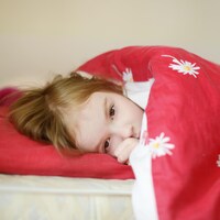 Une petite fille rousse dort dans son lit.