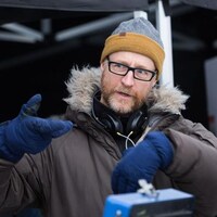Un cinéaste (Benoît Pilon) portant un manteau d'hiver, une tuque et des gants donne des directions à son équipe.
