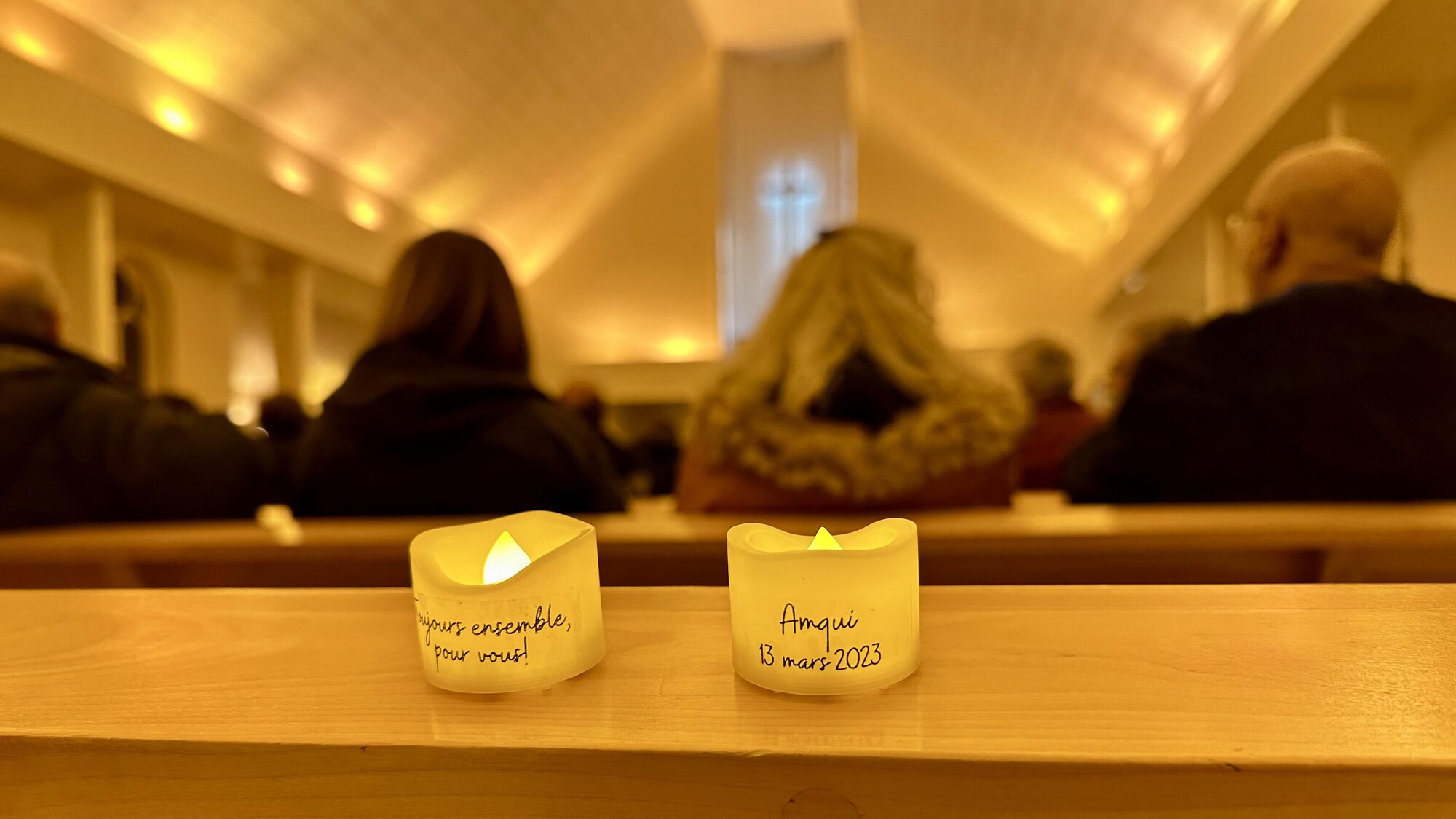 Deux chandelles dans l'église où il est écrit : Toujours ensemble, pour vous! Amqui, 13 mars 2023.
