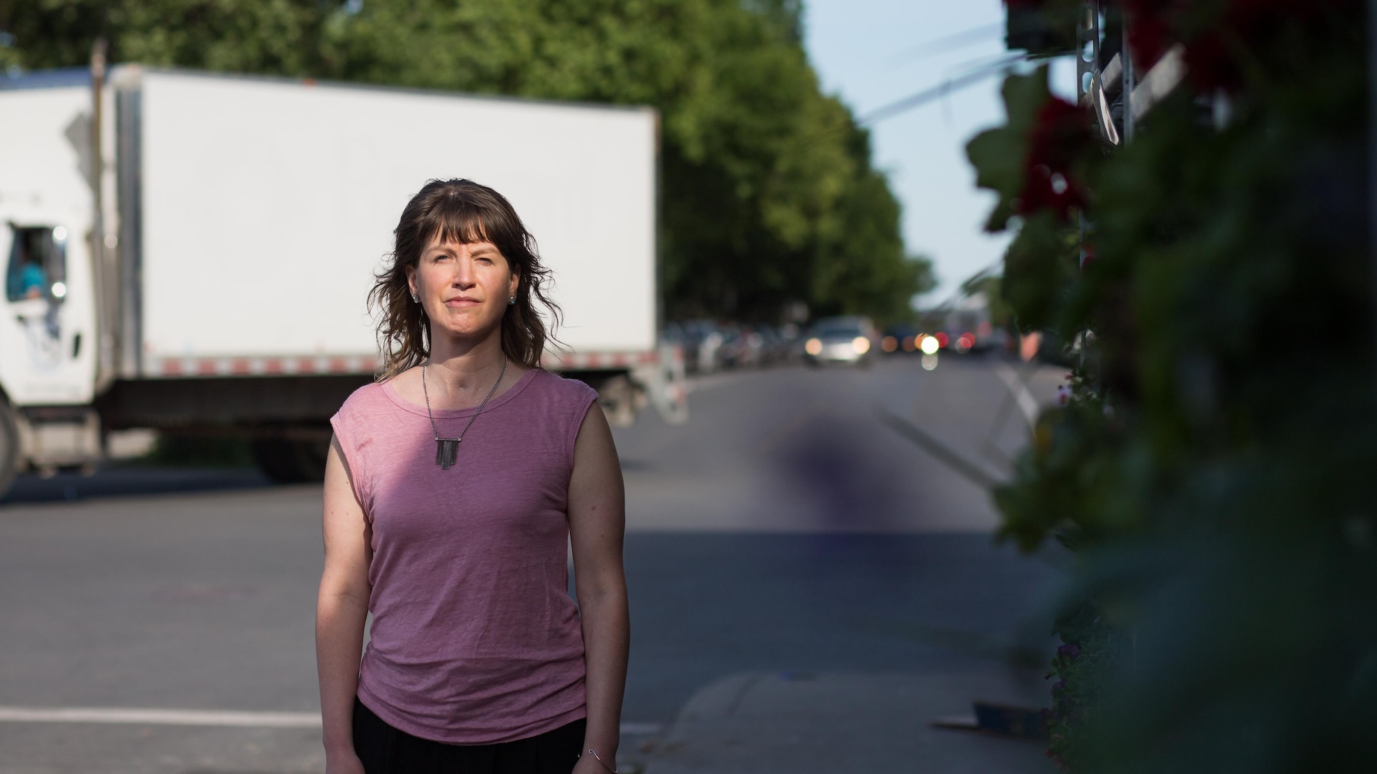 Audrey Talbot se tient droite sur le trottoir, face à la caméra. Derrière elle, un camion tourne le coin de la rue.