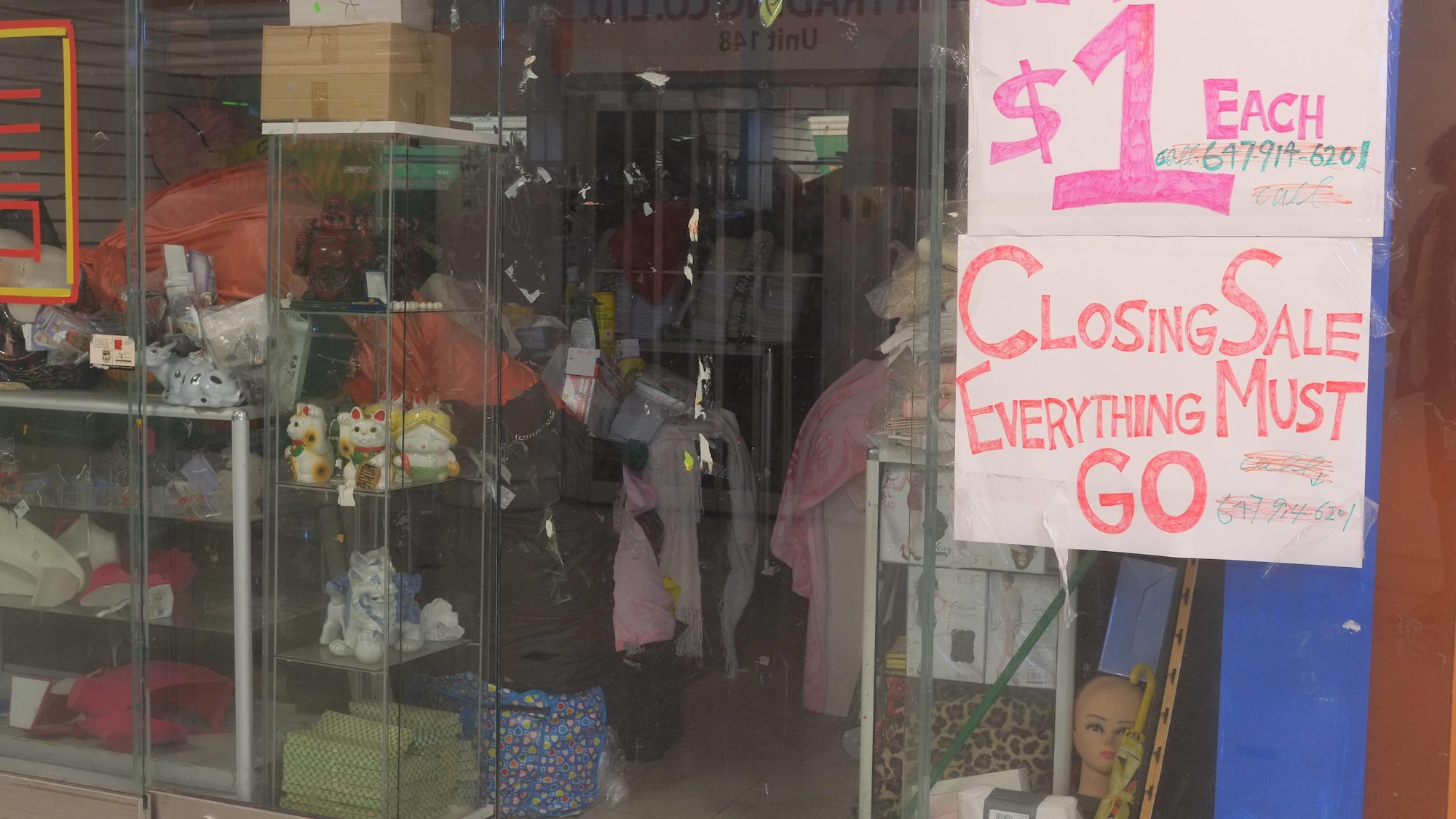 Un magasin fermé avec des produits à l'intérieur et un écriteau de vente finale dans la vitrine.
