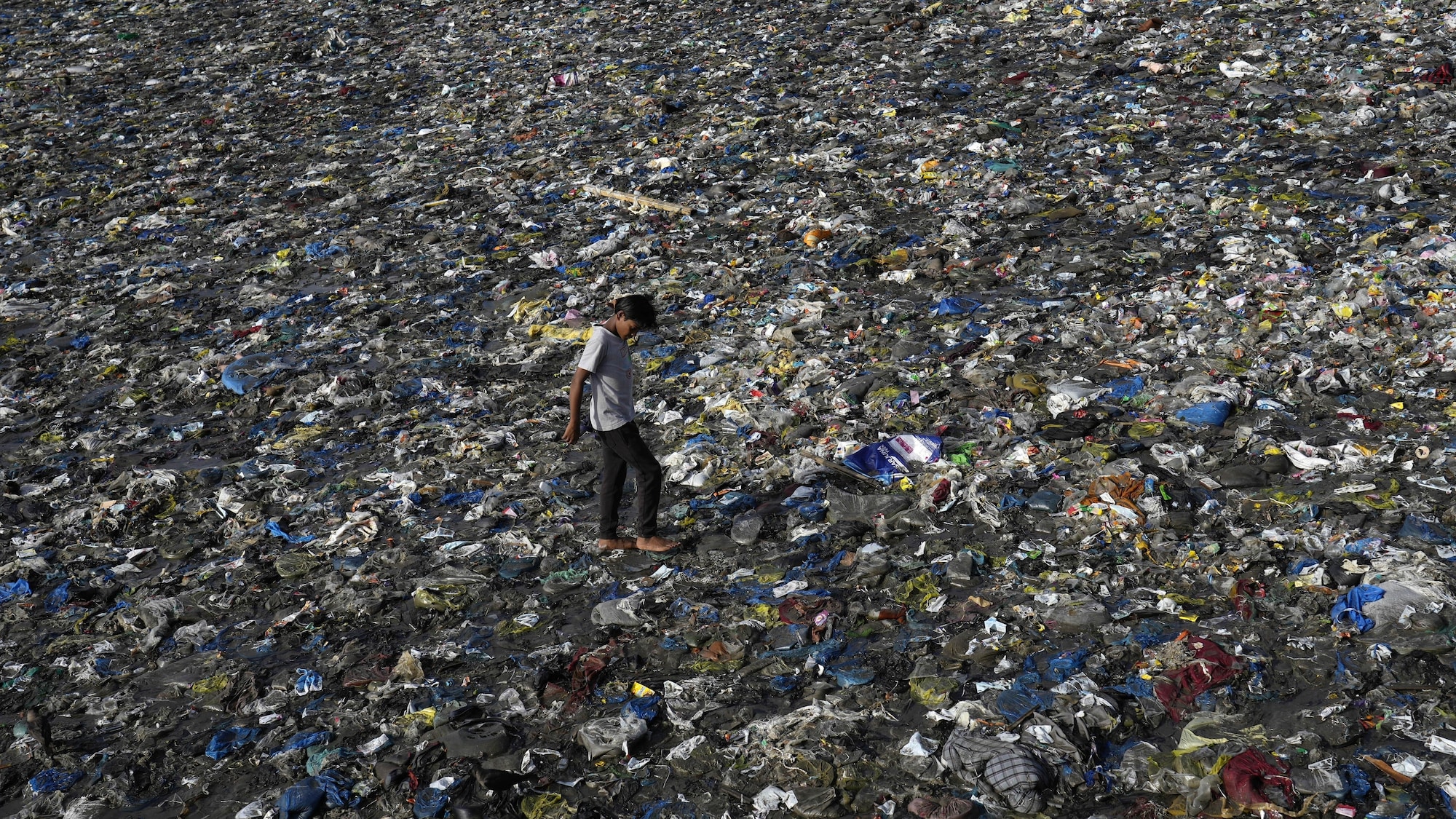 Un garçon marche au milieu de déchets, dont beaucoup sont en plastique, sur la plage de Badhwar Park, à Mumbai, en Inde, le 5 juin 2023.